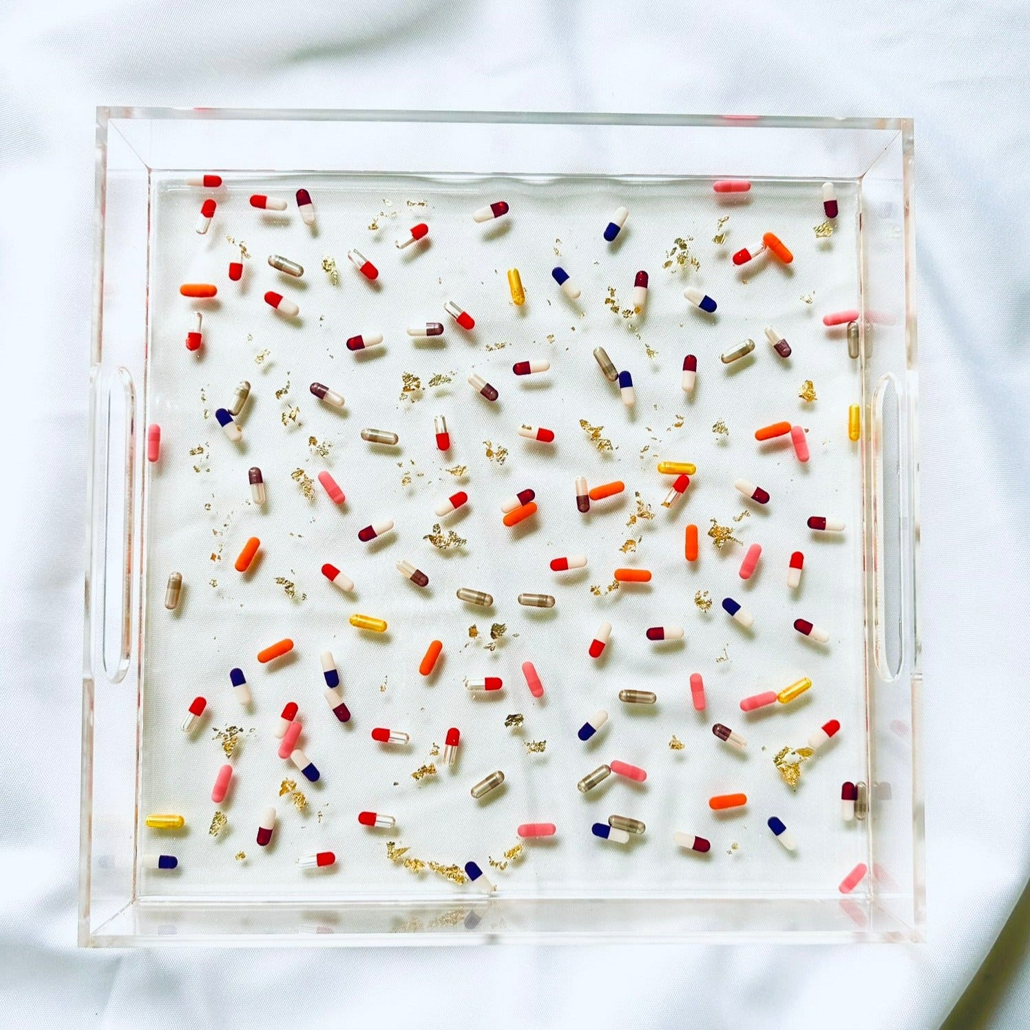 Handmade acrylic tray with gold leaf accents and multicolored pill designs on a white background.