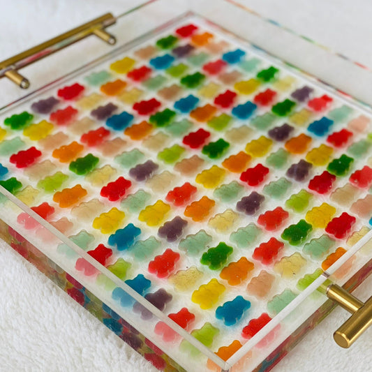 Handcrafted acrylic serving tray filled with colorful gummy bear candies, featuring gold handles and a glossy finish.