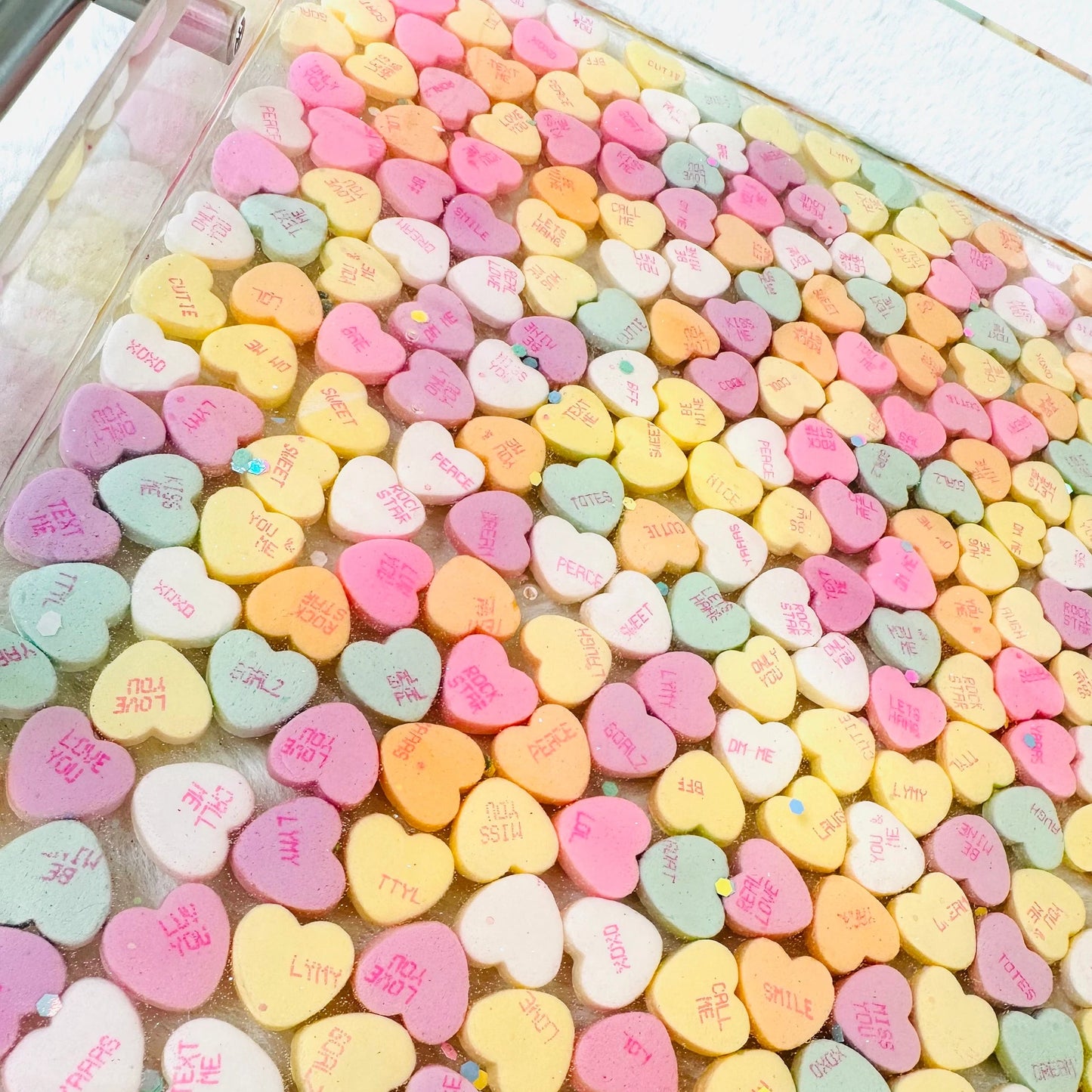 Clear acrylic serving tray with silver handles and filled with colorful conversation candy hearts, sealed in epoxy resin