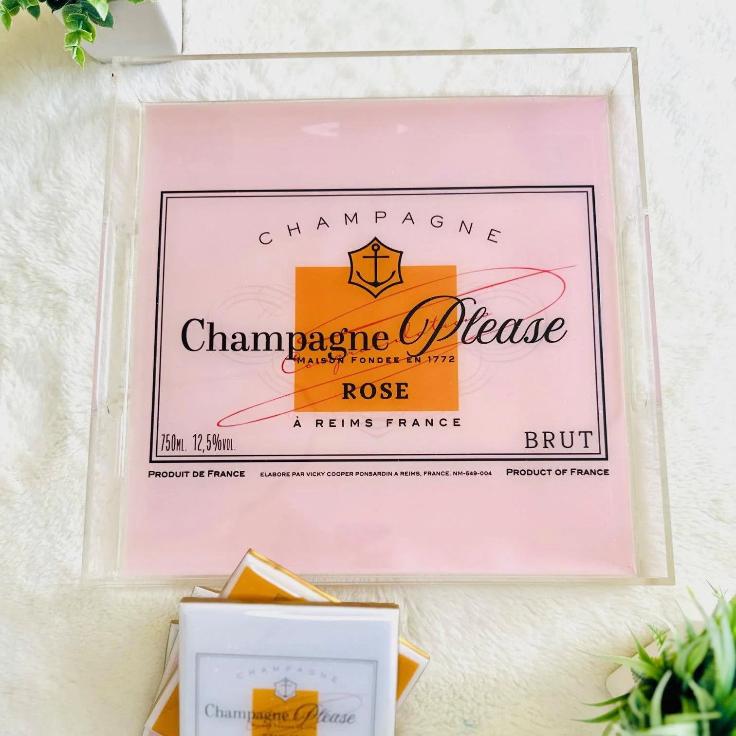 Champagne Please rose packaging on a white surface with greenery
